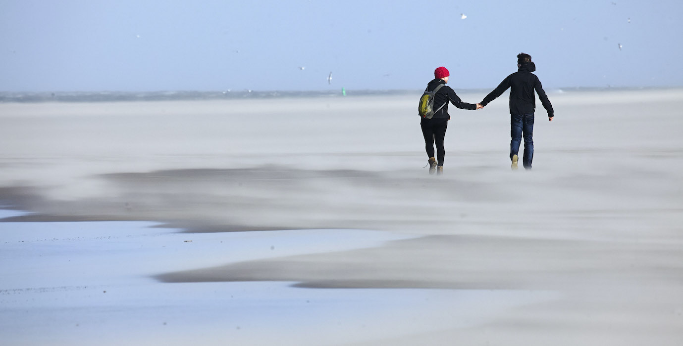 Two persons walking at the beach. 