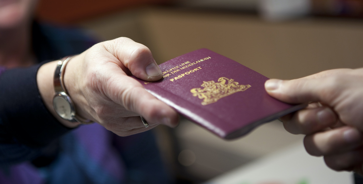 Someone gives a Dutch passport to a person. 