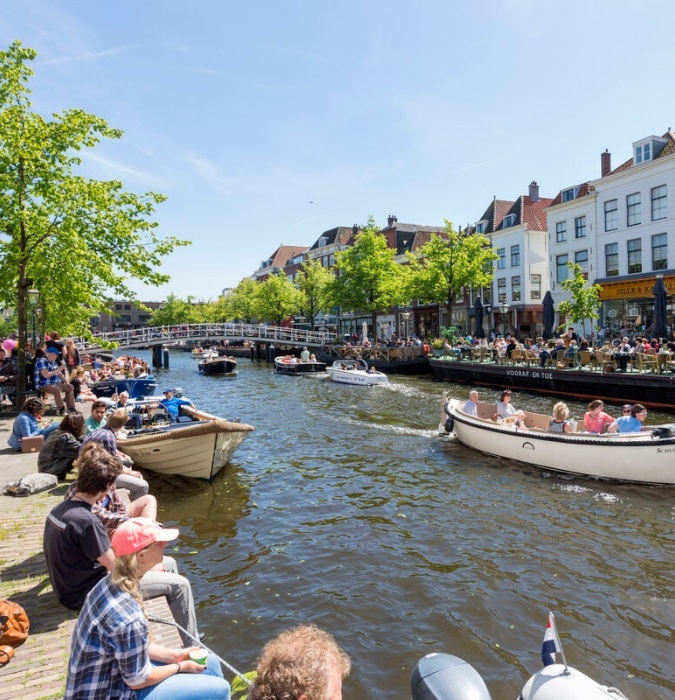 People enjoying the sun sitting down at the canals 